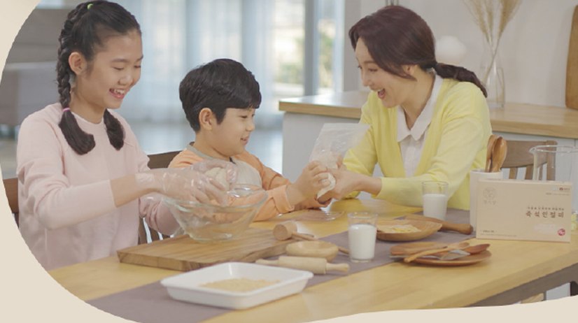 부엌 식탁에서 아이들과 엄마가 지퍼백을 주무르며 웃는 모습