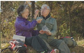 등산 중 바위에 앉아 인절미를 나눠 먹는 노부부