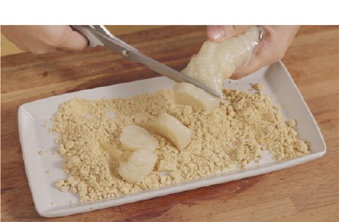 반죽을 가위로 잘라 콩고물 위에 올리는 모습