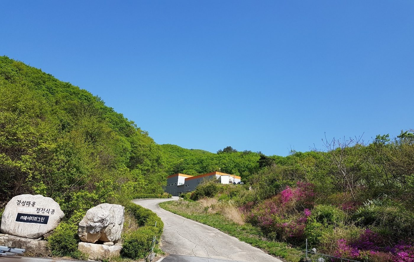 푸른 산자락 사이로 이어진 진입로와 입구 표지석